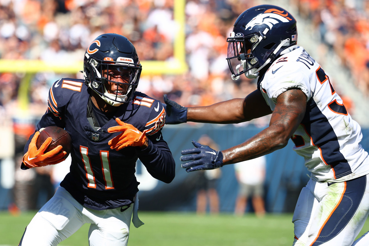 Darnell Mooney runs with the ball as a Broncos safety reaches out to tackle him