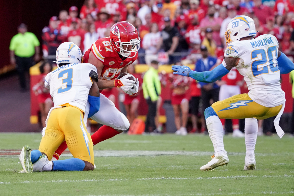 Kansas City Chiefs tight end Travis Kelce runs with the ball as Los Angeles Chargers safety Derwin James Jr. makes the tackle during the first half at GEHA Field at Arrowhead Stadium.