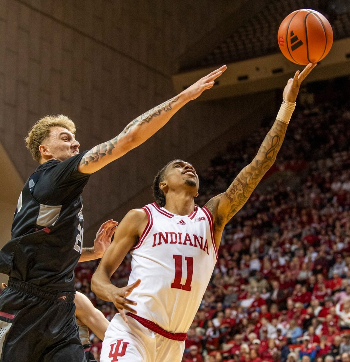 Indiana's CJ Gunn (11) shoots past University of Indianaplis' Julian Steindfeld (21) during the Indiana versus University of Indianapolis men's basketball game.