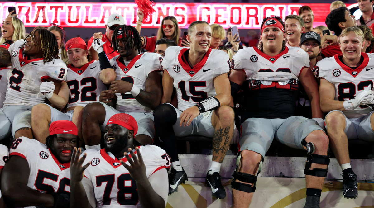 Georgia Bulldogs quarterback Carson Beck smiles with teammates, jumping into the stands after beating Florida.