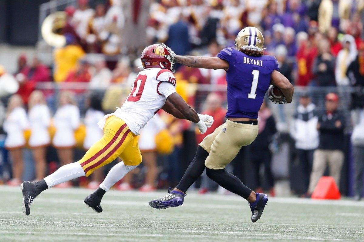 Husky tight end Hunter Bryant stiff-arms his way past a Trojan defender.
