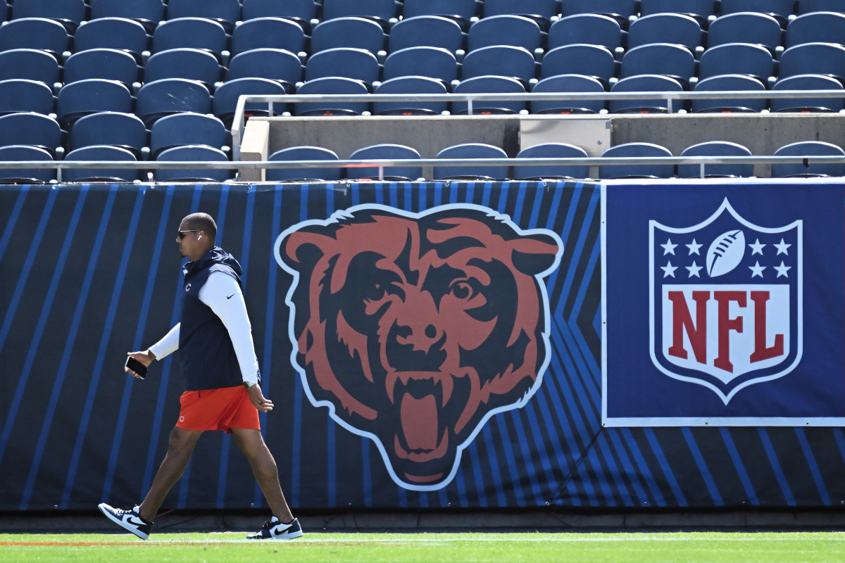Ryan Poles walks on the field in front of a big Bears logo on the stadium seating