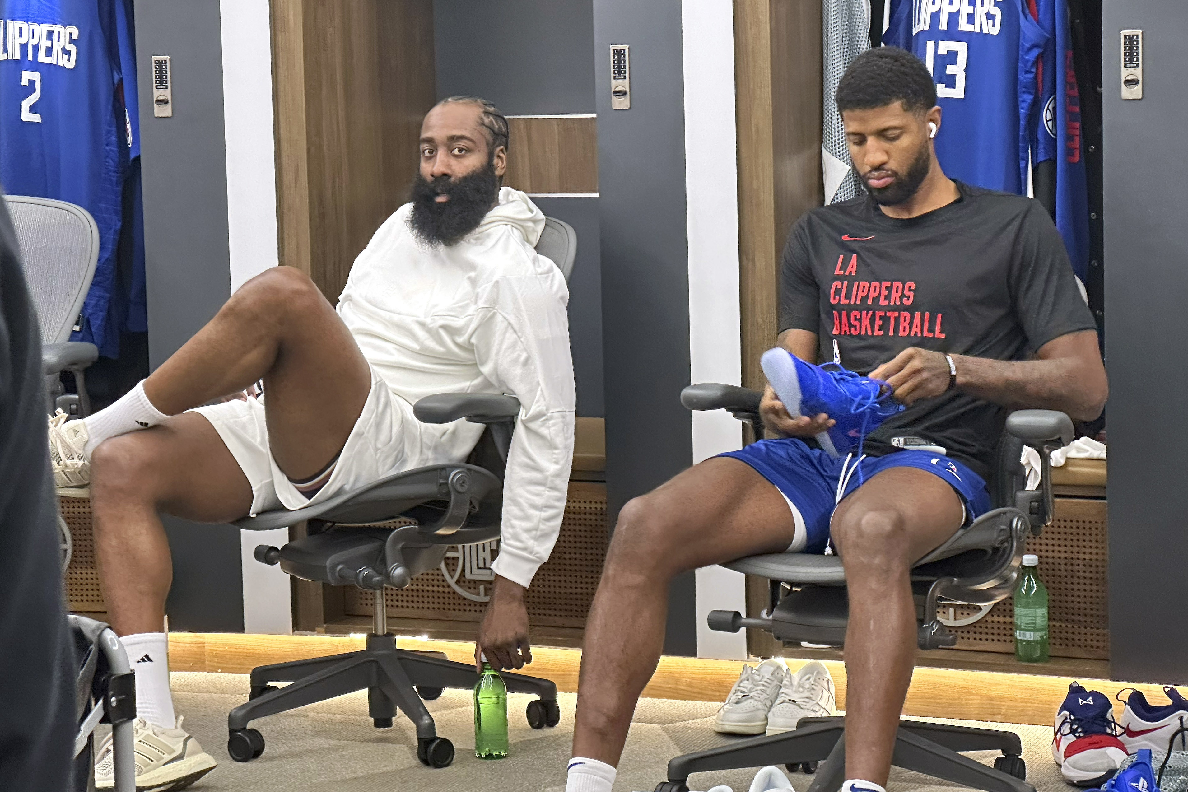 James Harden sits next to Los Angeles Clippers forward Paul George as he visits the locker room prior to the Clippers-Orlando Magic game on Tuesday, Oct. 31, 2023, in Los Angeles.