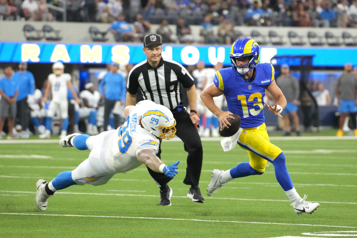 Aug 12, 2023; Inglewood, California, USA; Los Angeles Rams quarterback Stetson Bennett (13) is pursued by Los Angeles Chargers defensive tackle Scott Matlock (99) in the first half at SoFi Stadium. (Kirby Lee / USA TODAY Sports).