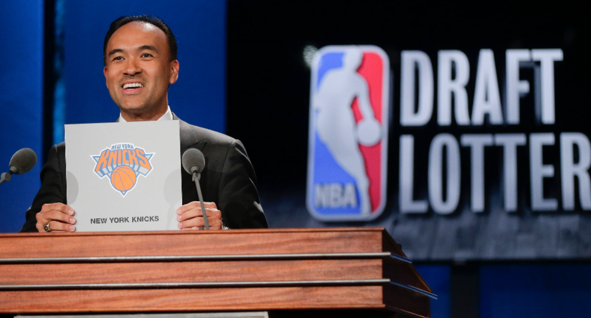NBA deputy commissioner Mark Tatum brandishes the Knicks' logo during an NBA draft lottery