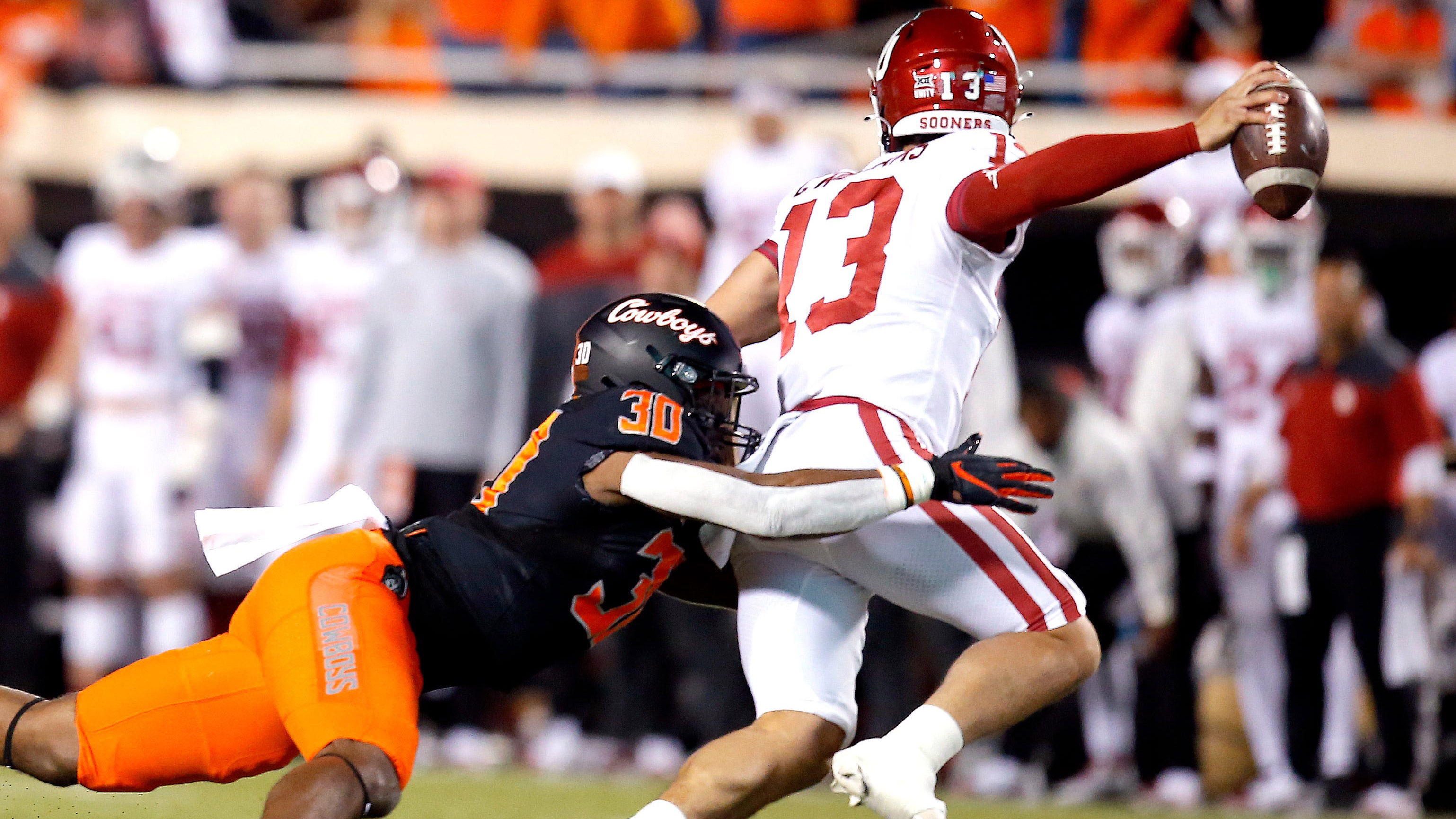 Oklahoma's Caleb Williams scrambles as he is pressured by Oklahoma State's Collin Oliver in the first quarter during a Bedlam college football game between the Oklahoma State University Cowboys.
