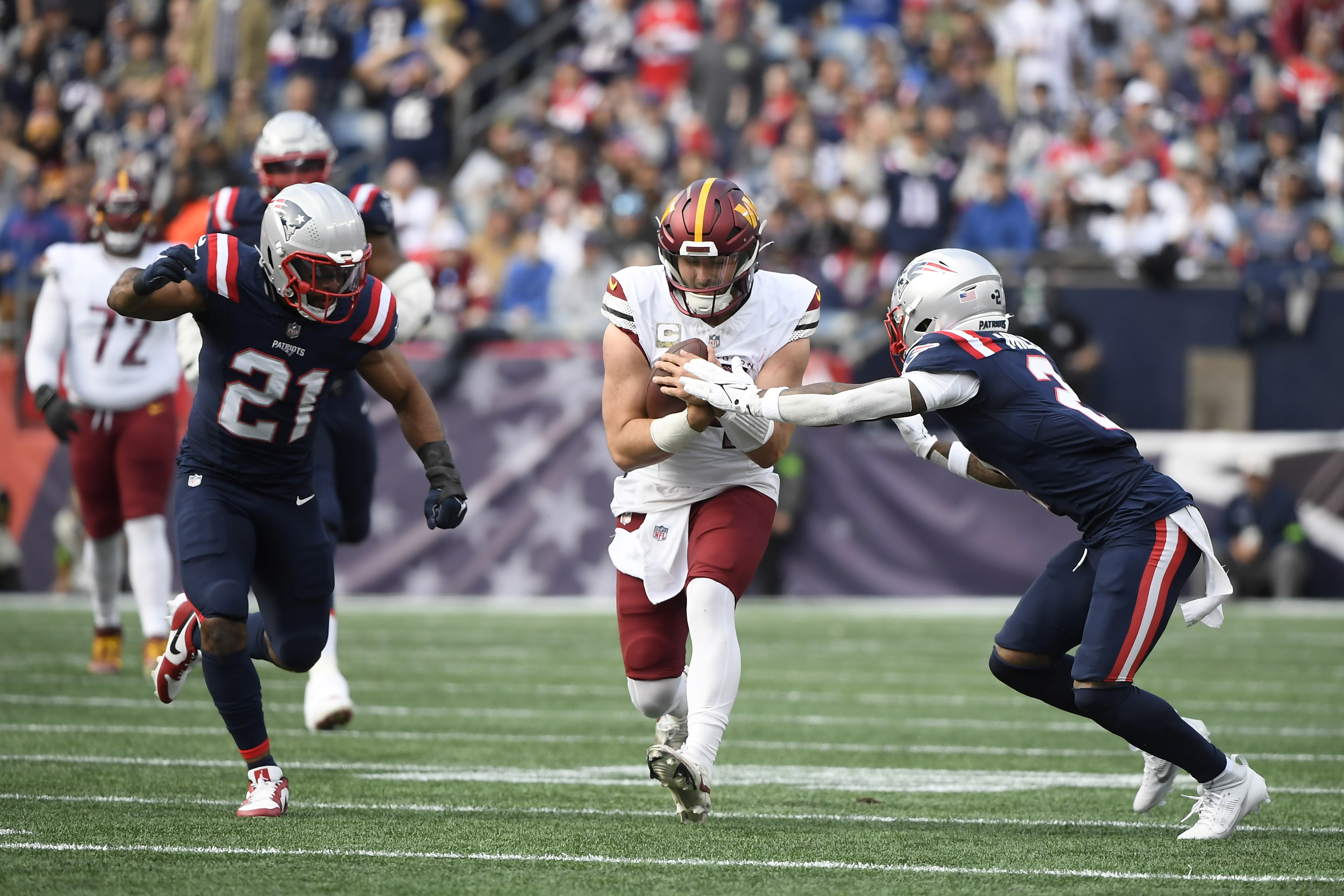 Washington Commanders quarterback Sam Howell (14) runs the ball between New England Patriots safety Adrian Phillips (21) and cornerback Myles Bryant (27) during the first half at Gillette Stadium.