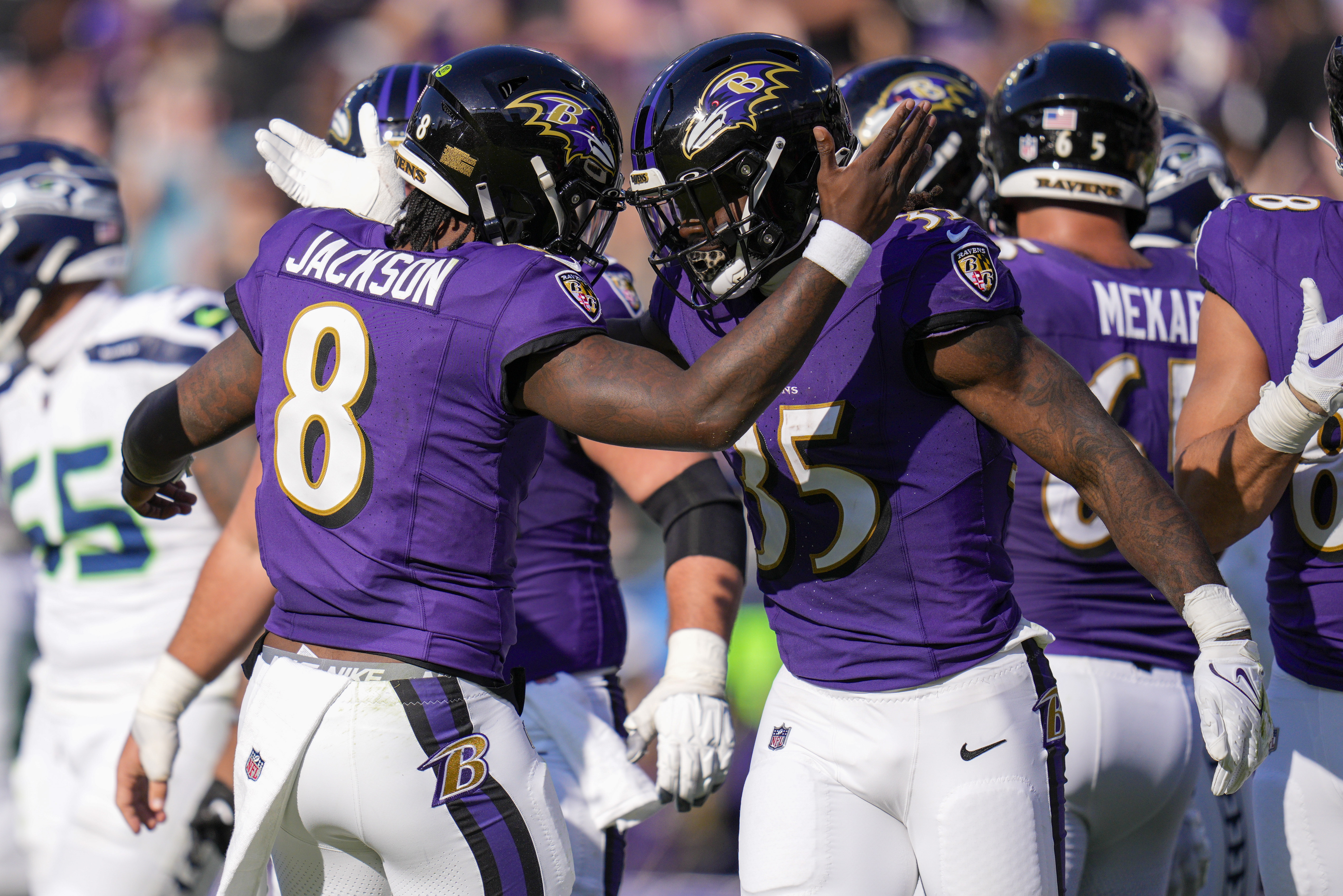 Lamar Jackson reaches out to tap Gus Edwards’s helmet in celebration