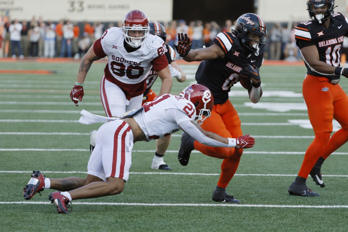 Nov 4, 2023; Stillwater, Oklahoma, USA; Oklahoma State Cowboys running back Ollie Gordon II (0) runs past Oklahoma Sooners defensive back Reggie Pearson (21) and defensive lineman Rondell Bothroyd (80) during a Bedlam college football game between the Oklahoma State University Cowboys (OSU) and the University of Oklahoma Sooners (OU) at Boone Pickens Stadium.
