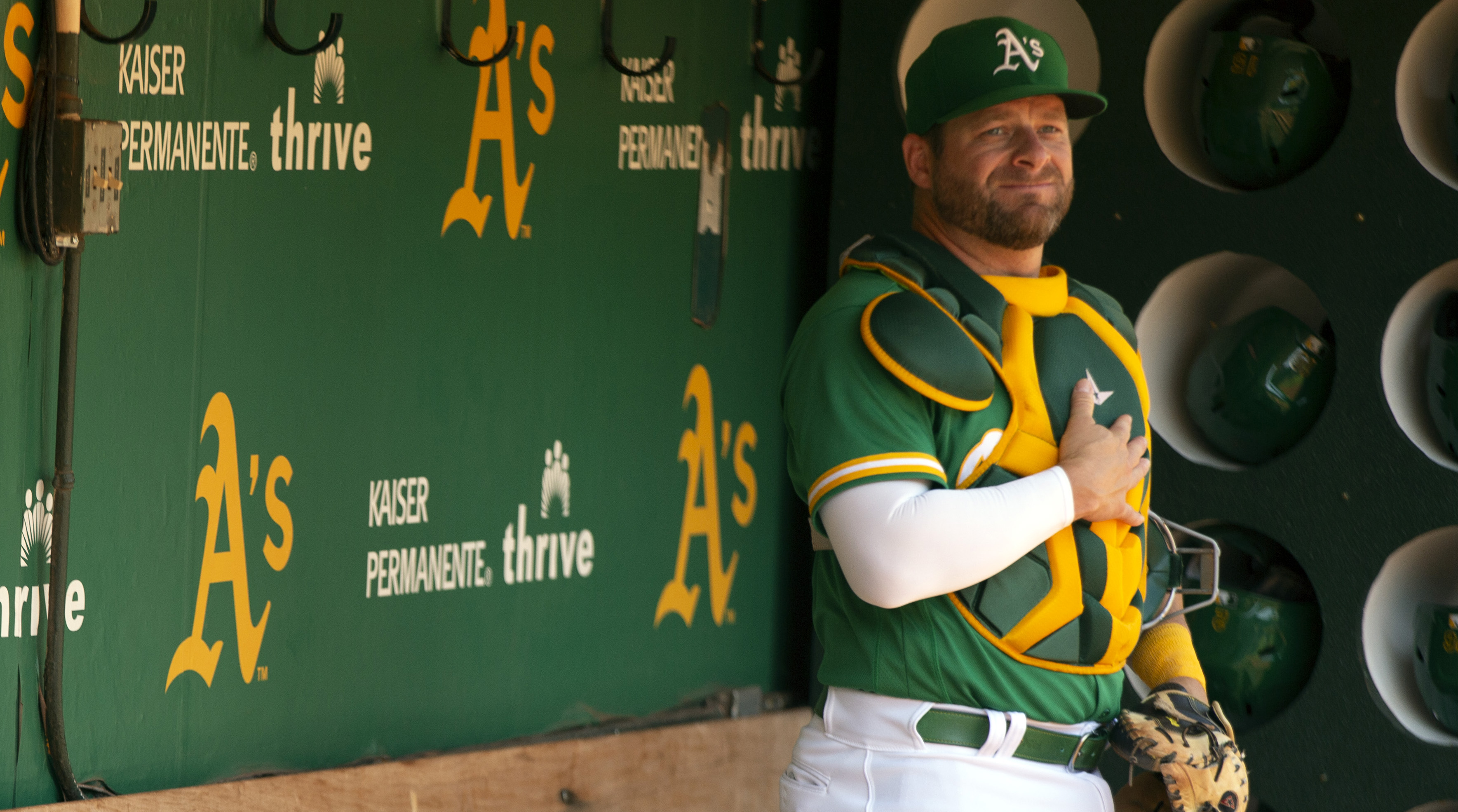 Stephen Vogt stands in the dugout wearing catchers’ gear with one hand over his heart