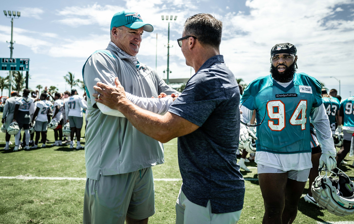 Larry Juriga, a member of Dolphins team security, shakes hands on a practice field.