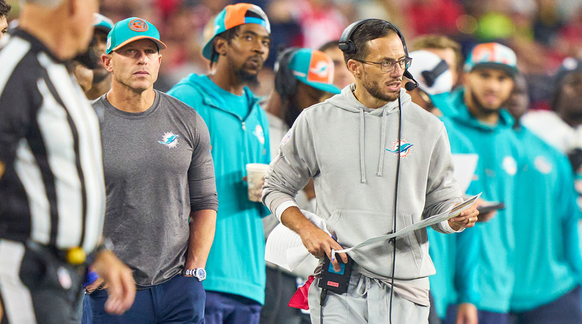 Dolphins director of team security Drew Brooks keeps an eye on Mike McDaniel during a game