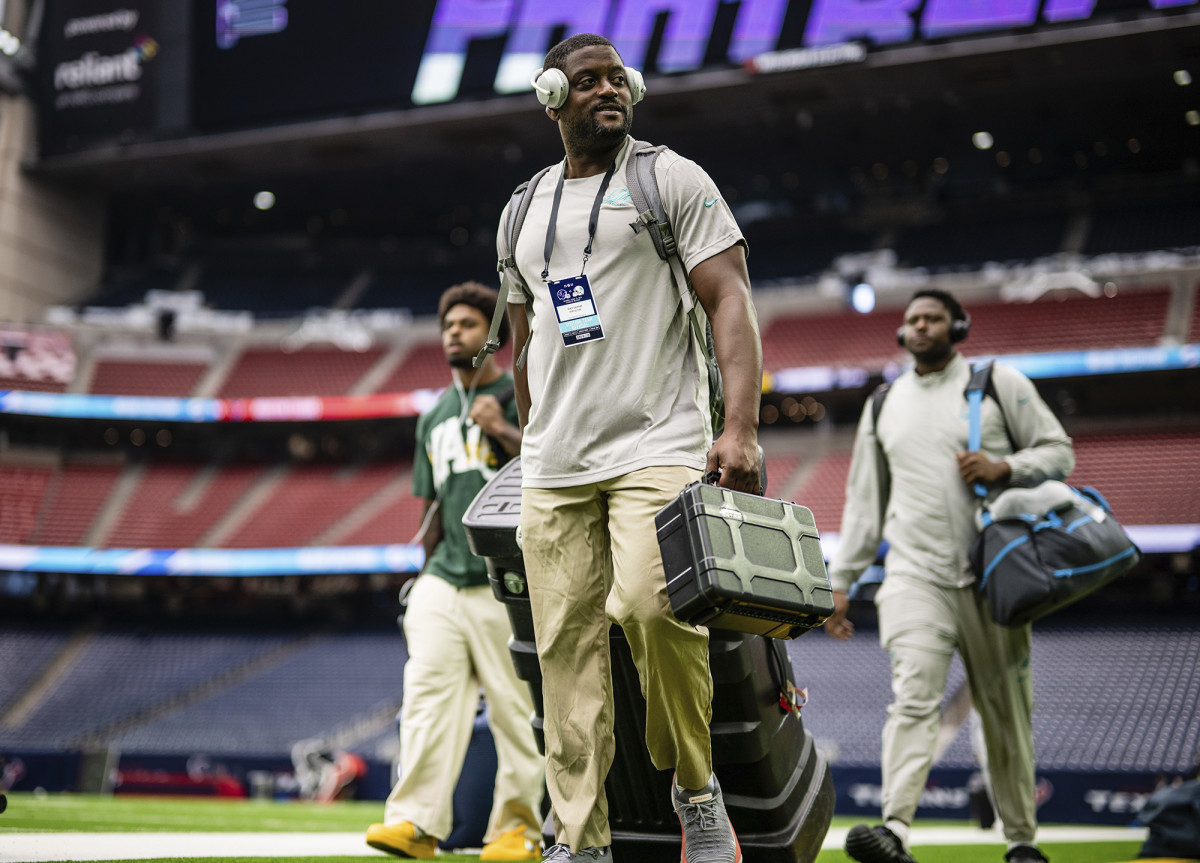 Dolphins football communications manager Renzo Sheppard walks on a field before a game.