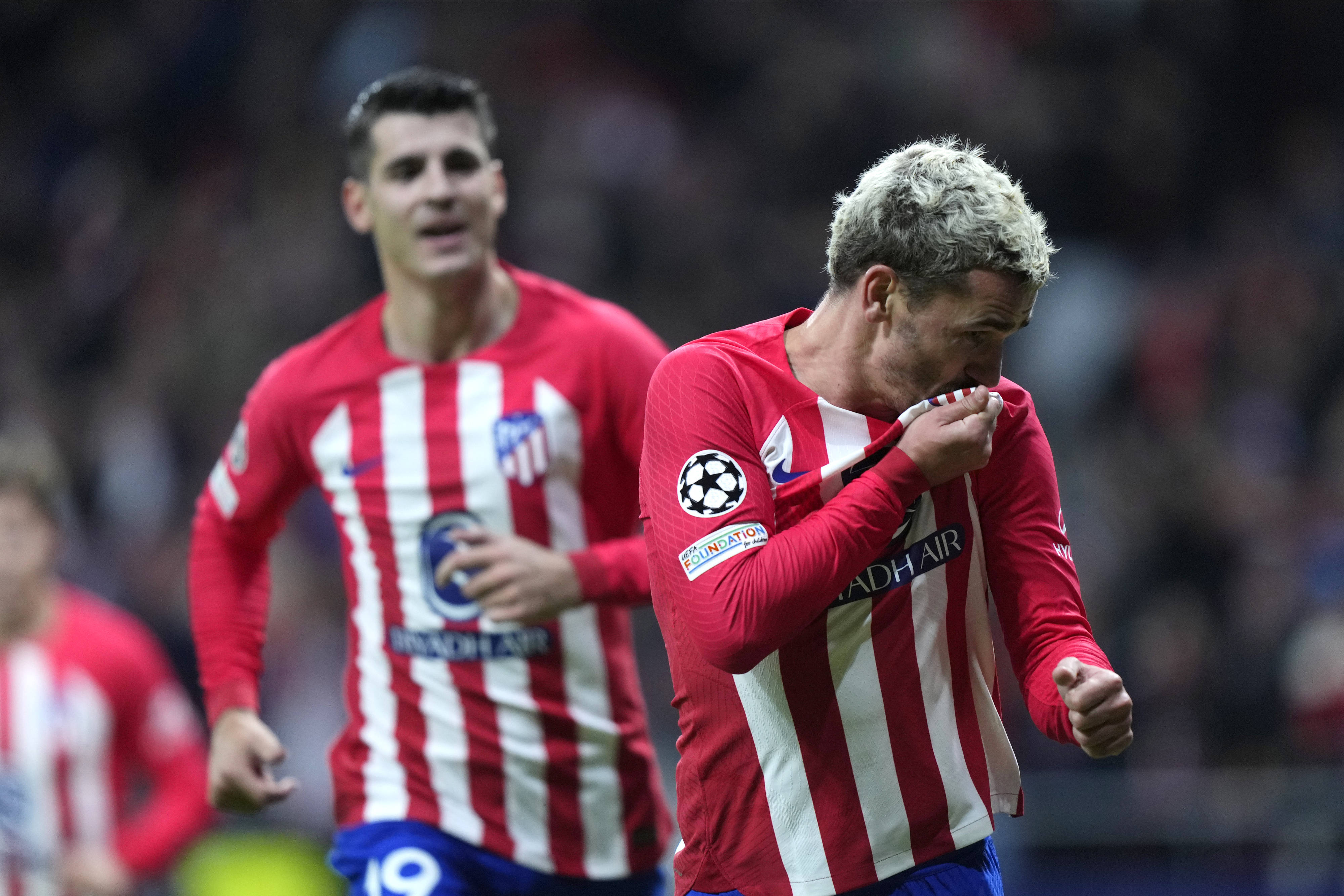 Antoine Griezmann pictured (right) kissing the badge on his Atletico Madrid shirt after scoring against Celtic in November 2023