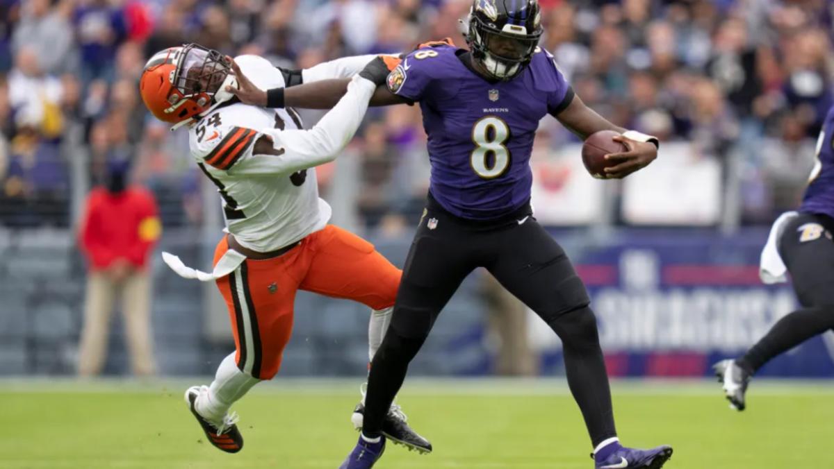 Ravens quarterback Lamar Jackson stiff-arms a Browns defender.