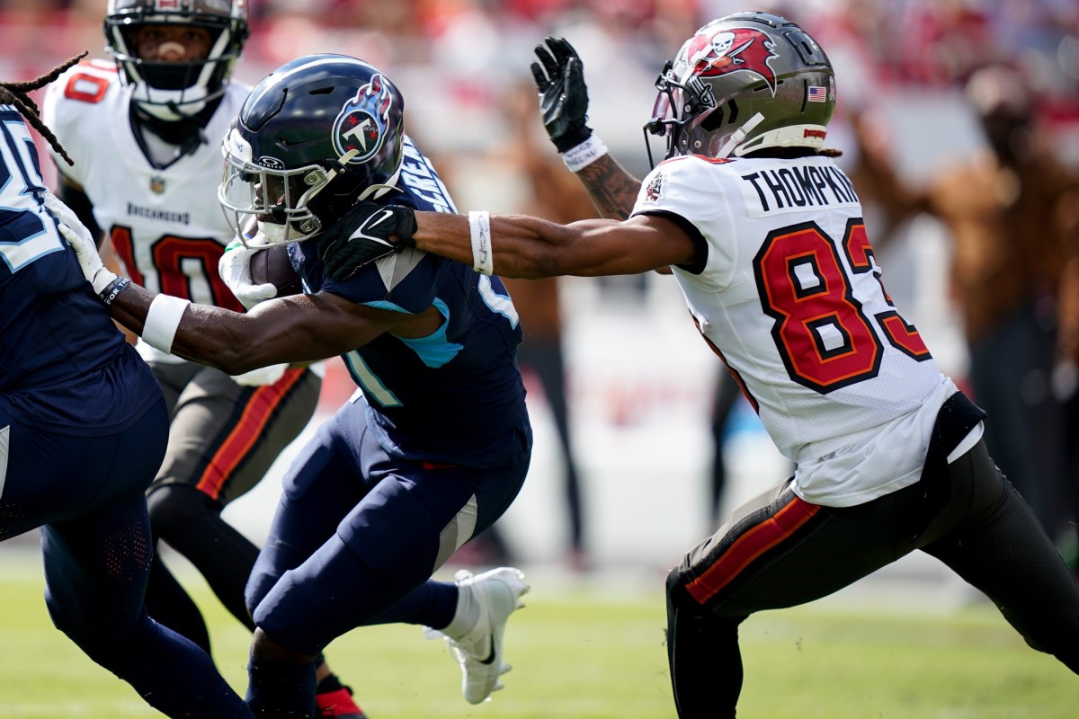 Tennessee Titans cornerback Roger McCreary (21) runs the ball under pressure from Tampa Bay Buccaneers wide receiver Deven Thompkins (83) after intercepting a Buccaneers pass .