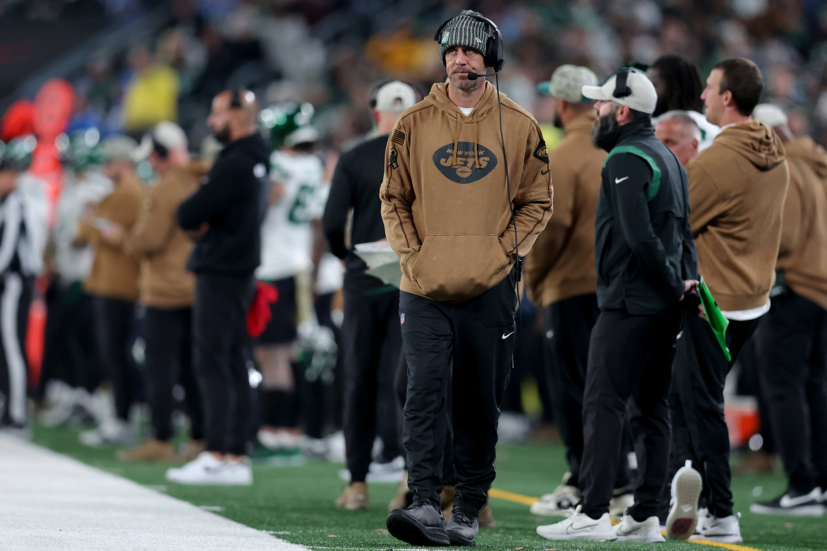 Aaron Rodgers walks along the sideline wearing a headset