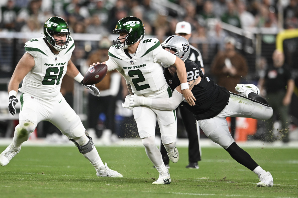 Zach Wilson tries to run with the ball in one hand as Maxx Crosby tackles him from behind