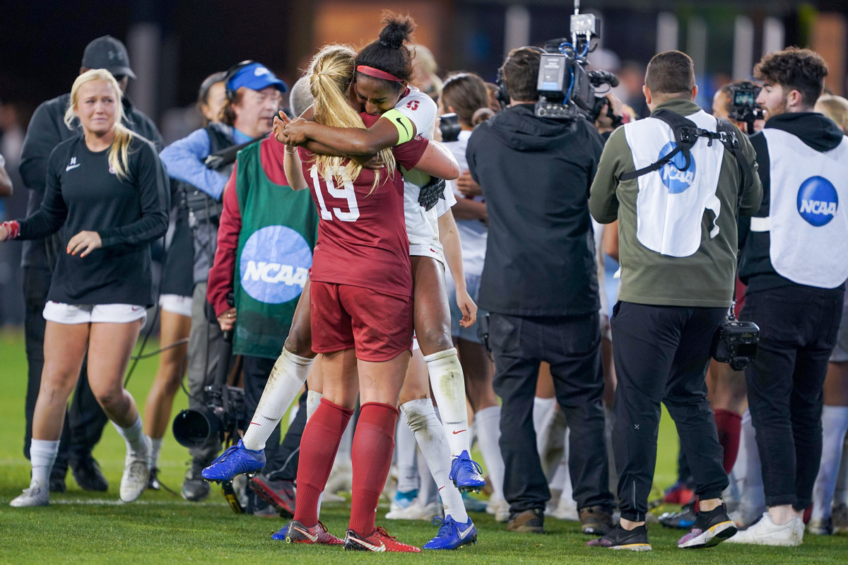 Katie Meyer and Naomi Girma hug on the field after winning the national championship.