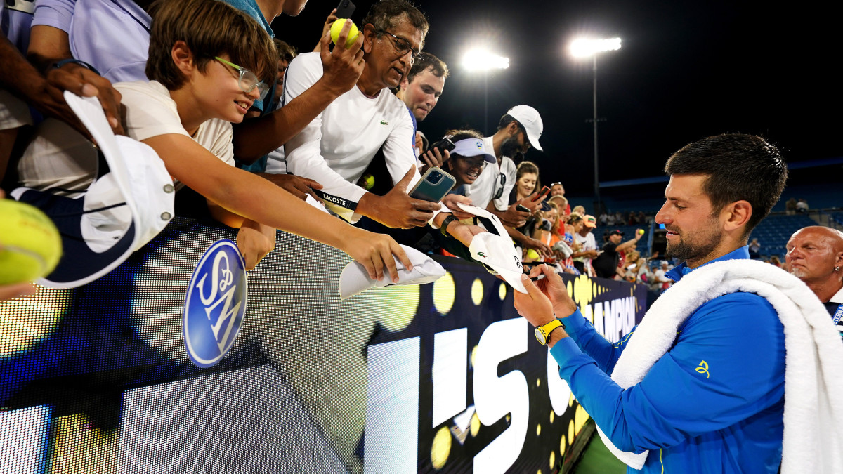 Novak Djokovic signs autographs for fans.