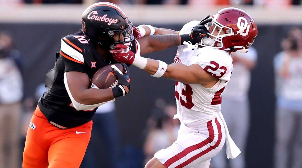 Oklahoma State's Rashod Owens (left) stiff-arms Oklahoma's Jasiah Wagoner.