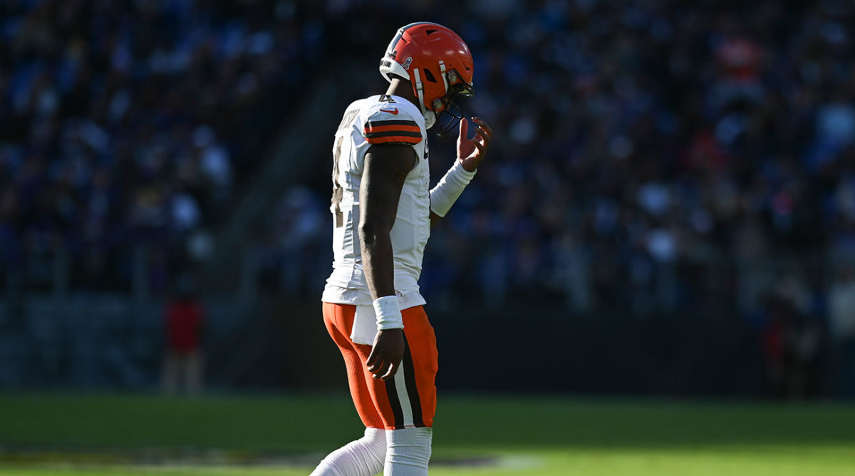 Deshaun Watson walks to the sidelines, alone in the frame with his head down.