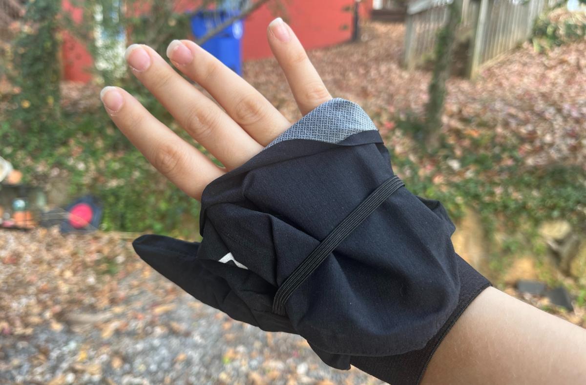 A tester's hand is pictured outside wearing the Salomon Bonatti gloves with the mitten portion tucked behind the included elastic.