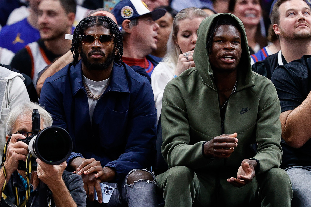 University of Colorado Buffaloes football players Shedeur Sanders (L) and Travis Hunter (R) watch during the third period between the Denver Nuggets and the Los Angeles Lakers at Ball Arena