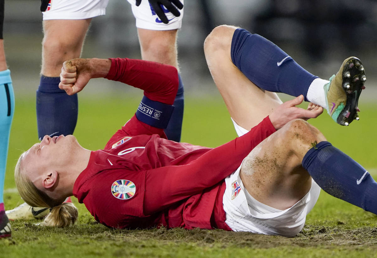 Erling Haaland pictured holding his left ankle after sustaining an injury during Norway's 2-0 win over the Faroe Islands in November 2023
