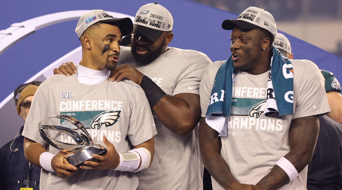 Jalen Hurts stands next to A.J. Brown holding the NFC championship trophy.