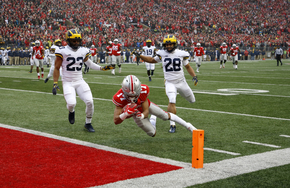 Ohio State’s Chris Olave dives into the end zone, trailed by two Michigan defenders.