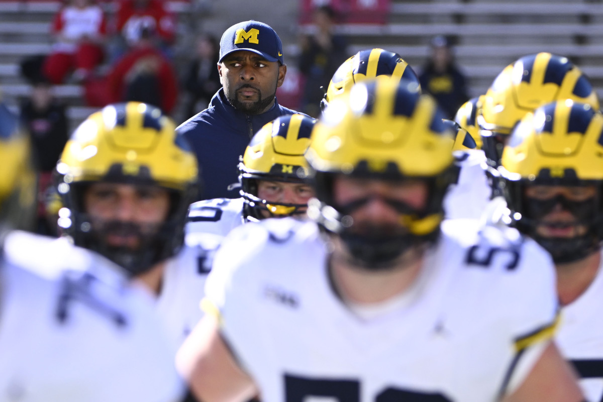 Interim head coach Sherrone Moore stands behind Michigan football players.