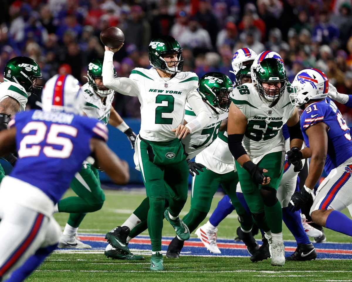 Zach Wilson reaches one hand up to throw the football as Bills and Jets players try to block each other around him