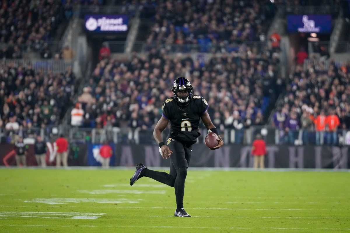 Lamar Jackson runs down the field holding the ball in one hand