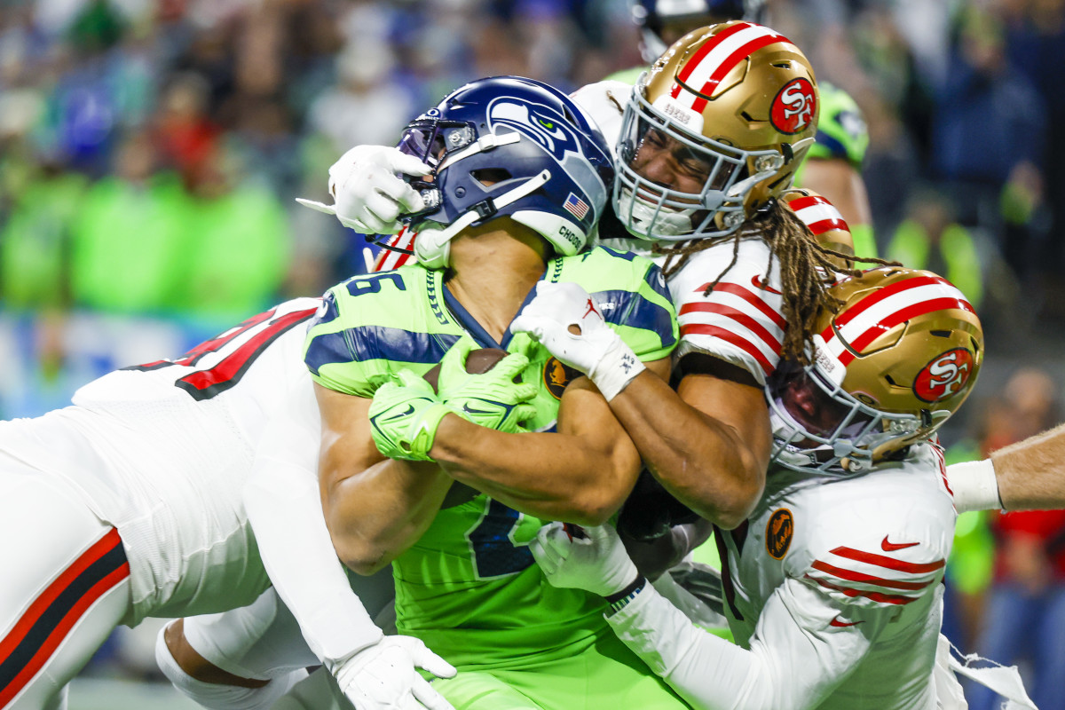 San Francisco 49ers linebacker Fred Warner (54) and linebacker Randy Gregory (5) tackle Seattle Seahawks running back Zach Charbonnet (26) on a rushing attempt.