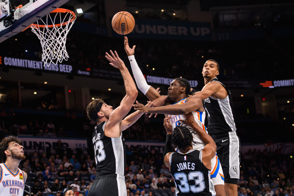 Oct 9, 2023; Oklahoma City, Oklahoma, USA; Oklahoma City Thunder forward Jalen Williams (8) shoots the ball while defended by San Antonio Spurs guard Tre Jones (33) and forward Zach Collins (23) during the first half at Paycom Center.