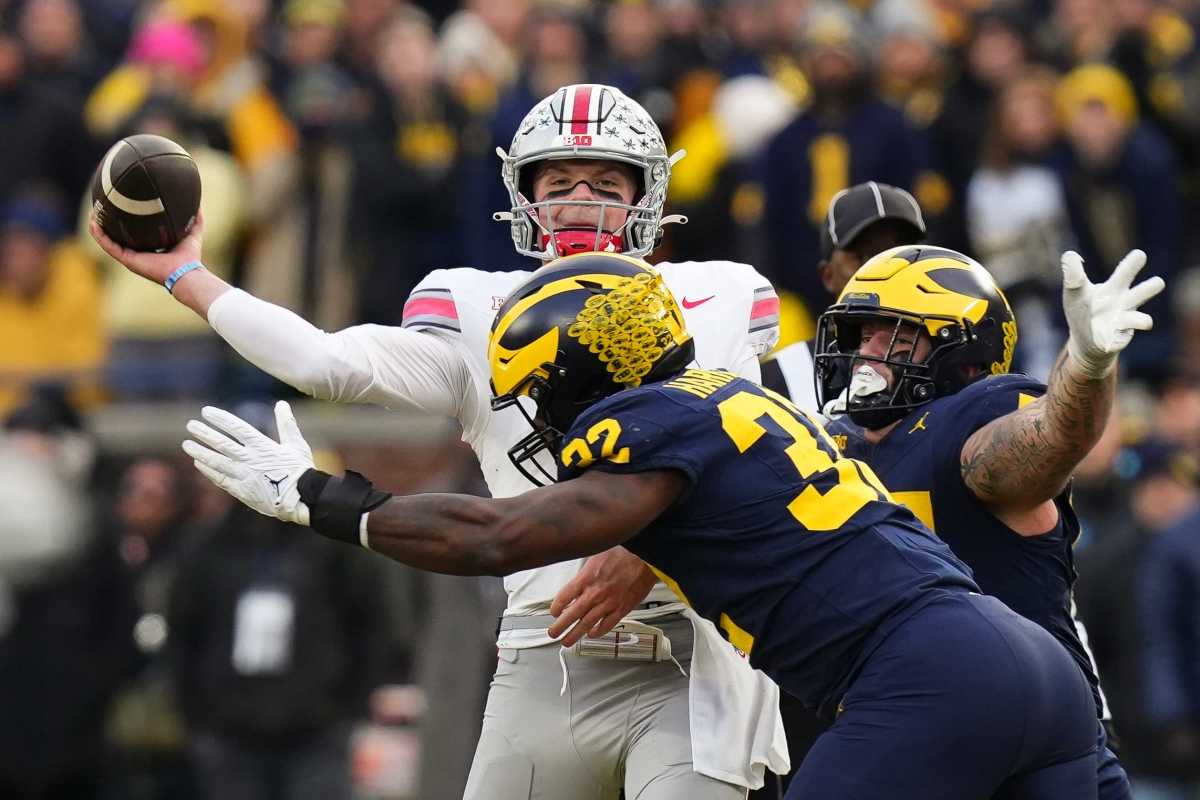 Ohio State Buckeyes quarterback Kyle McCord is hit by Michigan Wolverines defensive end Jaylen Harrell