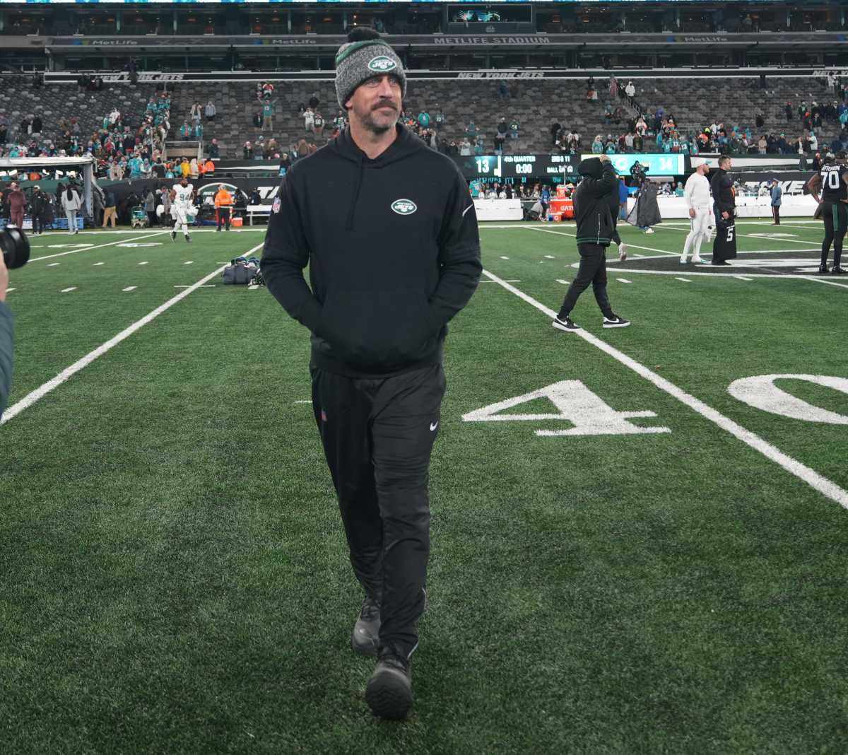 Aaron Rodgers walks on the field with both hands in his pockets