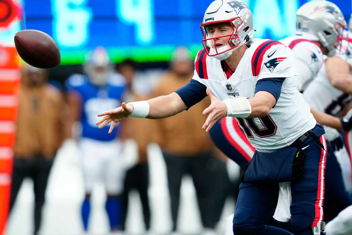 New England Patriots QB Mac Jones attempts a toss to a teammate against the New York Giants in Week 12; 26 Nov. 2023