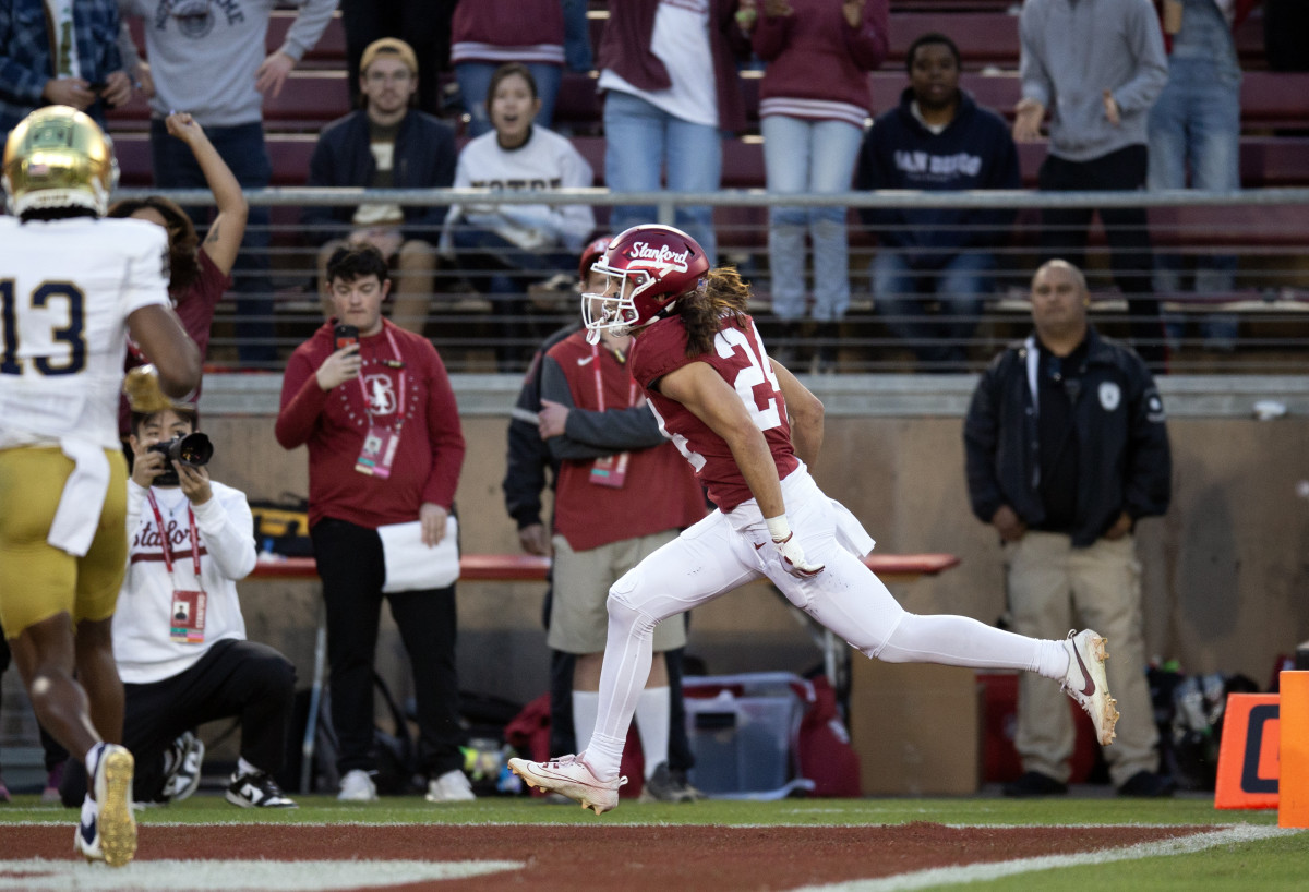 Nov 25, 2023; Stanford, California, USA; Stanford Cardinal wide receiver Tiger Bachmeier (24) runs the ball in for a touchdown ahead of Notre Dame Fighting Irish safety Thomas Harper (13) during the first quarter at Stanford Stadium. Mandatory Credit: D. Ross Cameron-USA TODAY Sports