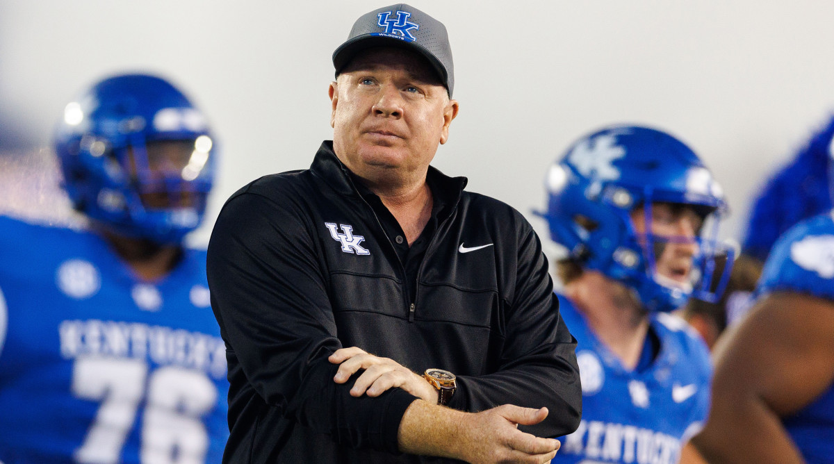 Kentucky Wildcats head coach Mark Stoops pulls up his sleeves while running onto the field with his players.