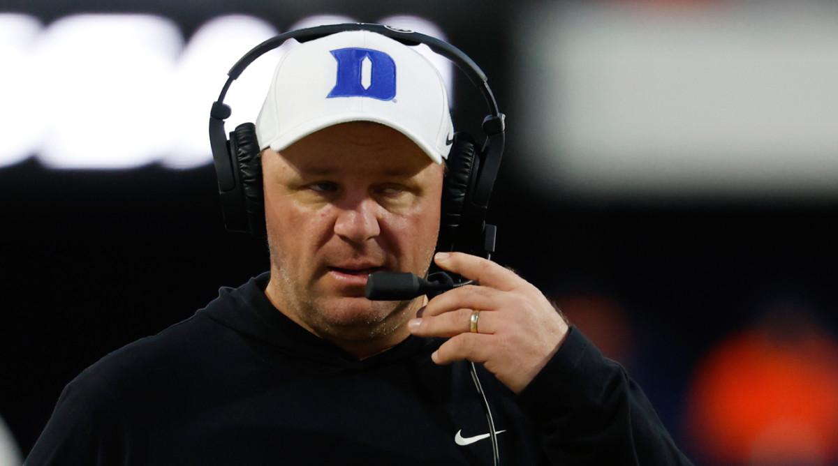 Former Duke coach Mike Elko speaks into the headset on the sideline.