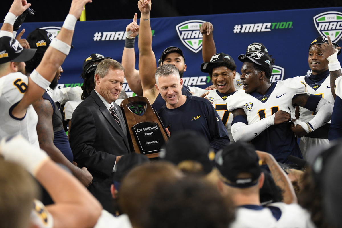 Dec 3, 2022; Detroit, Michigan, USA; MAC Commissioner Dr. Jon Steinbrecher (center left) hands the MAC Championship trophy to Toledo head coach Jason Candle after Toledo beat Ohio University at Ford Field. Mandatory Credit: Lon Horwedel-USA TODAY Sports