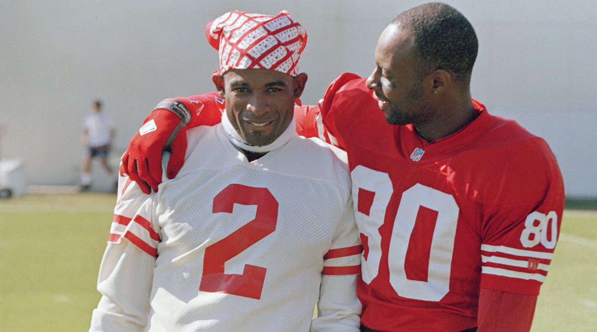 Jerry Rice, right, puts his arm around Deion Sanders on the practice field as members of the San Francisco 49ers