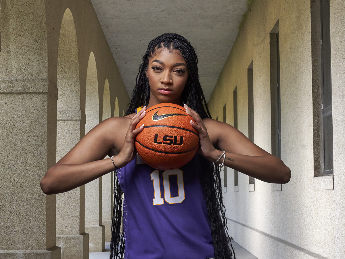 LSU forward Angel Reese poses holding a basketball with LSU’s logo on it.
