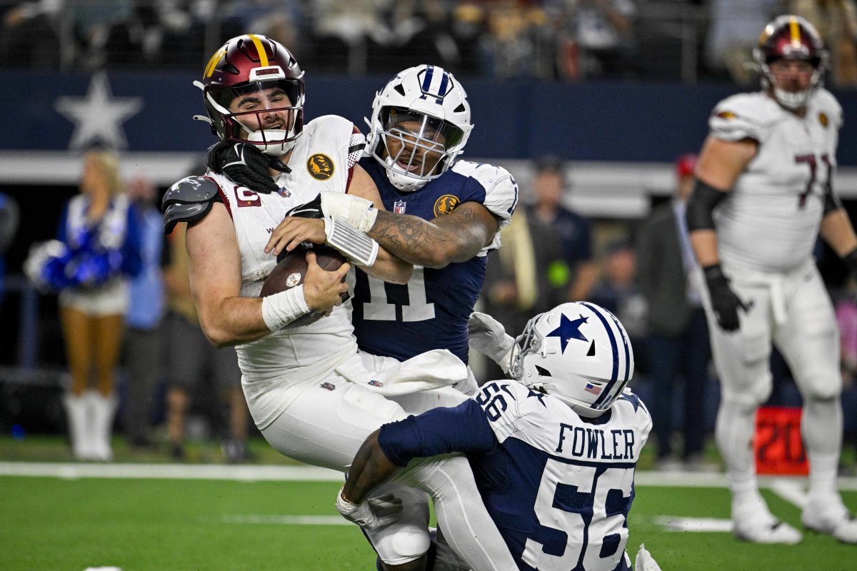 Sam Howell tries to hang onto the ball as two Cowboys defenders tackle him