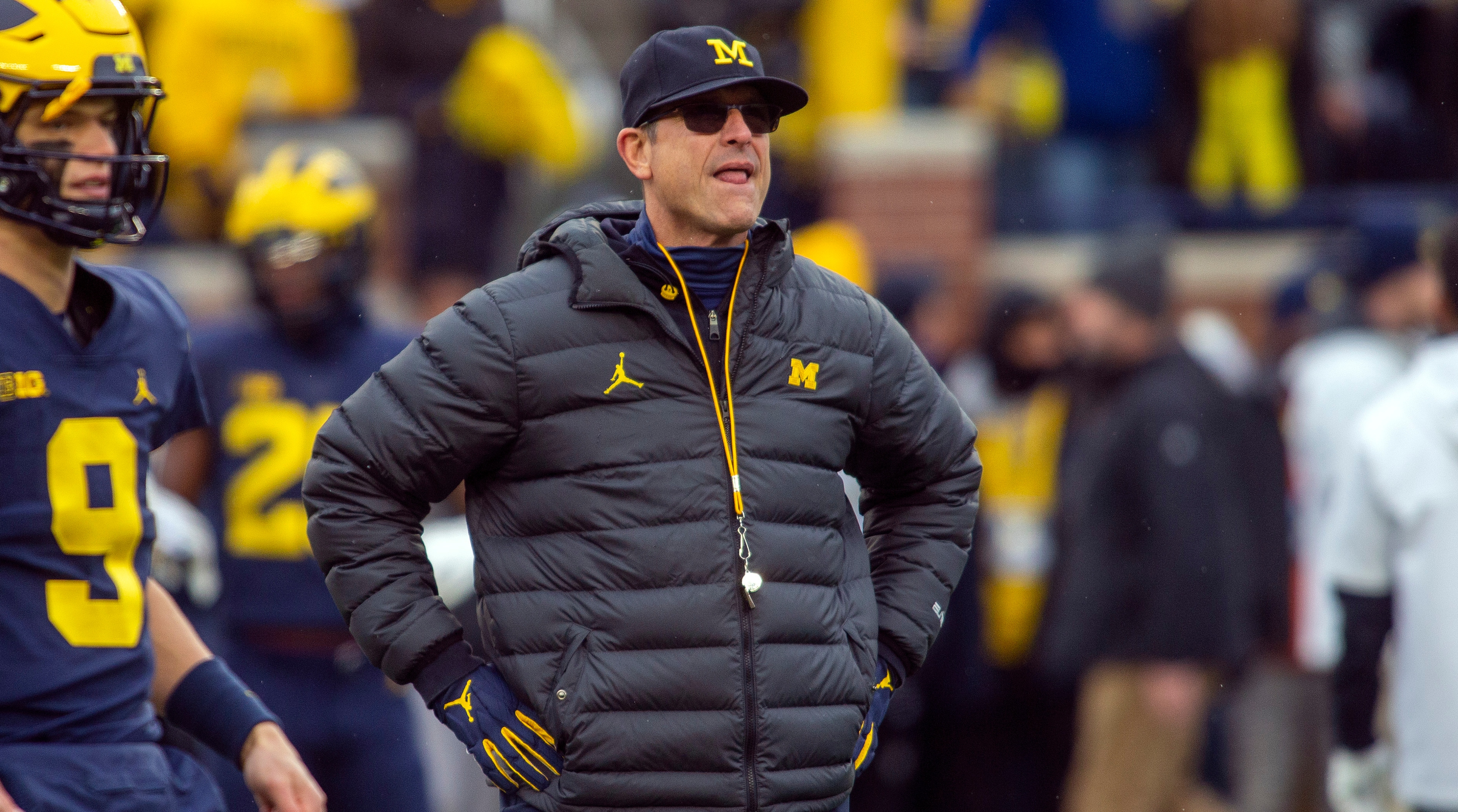 Michigan football coach Jim Harbaugh stands with his hands on his hips while on the sideline during a game against Ohio State.