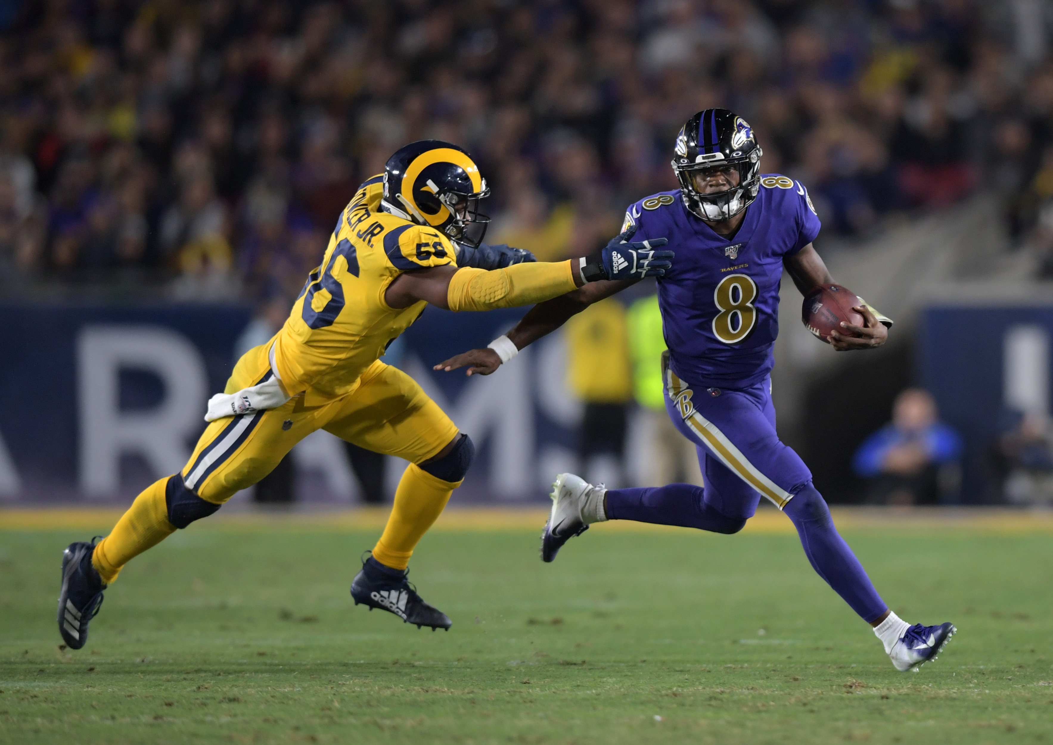 Nov 25, 2019; Los Angeles, CA, USA; Baltimore Ravens quarterback Lamar Jackson (8) is pursued by Los Angeles Rams defensive end Dante Fowler (56) in the third quarter at Los Angeles Memorial Coliseum. The Ravens defeated the Rams 45-6. 