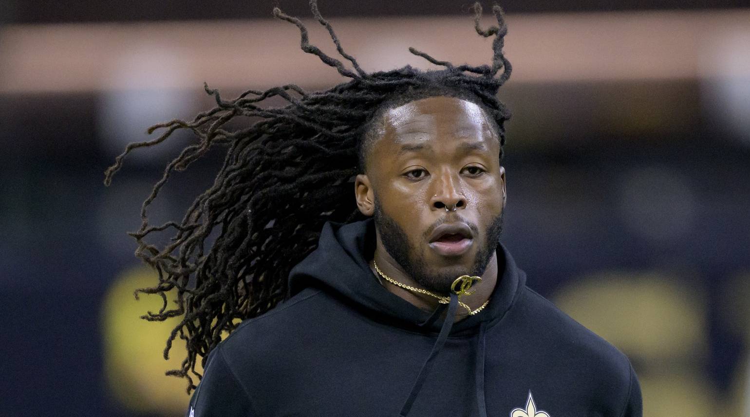 Saints running back Alvin Kamara jogs on a field while warming up before a game