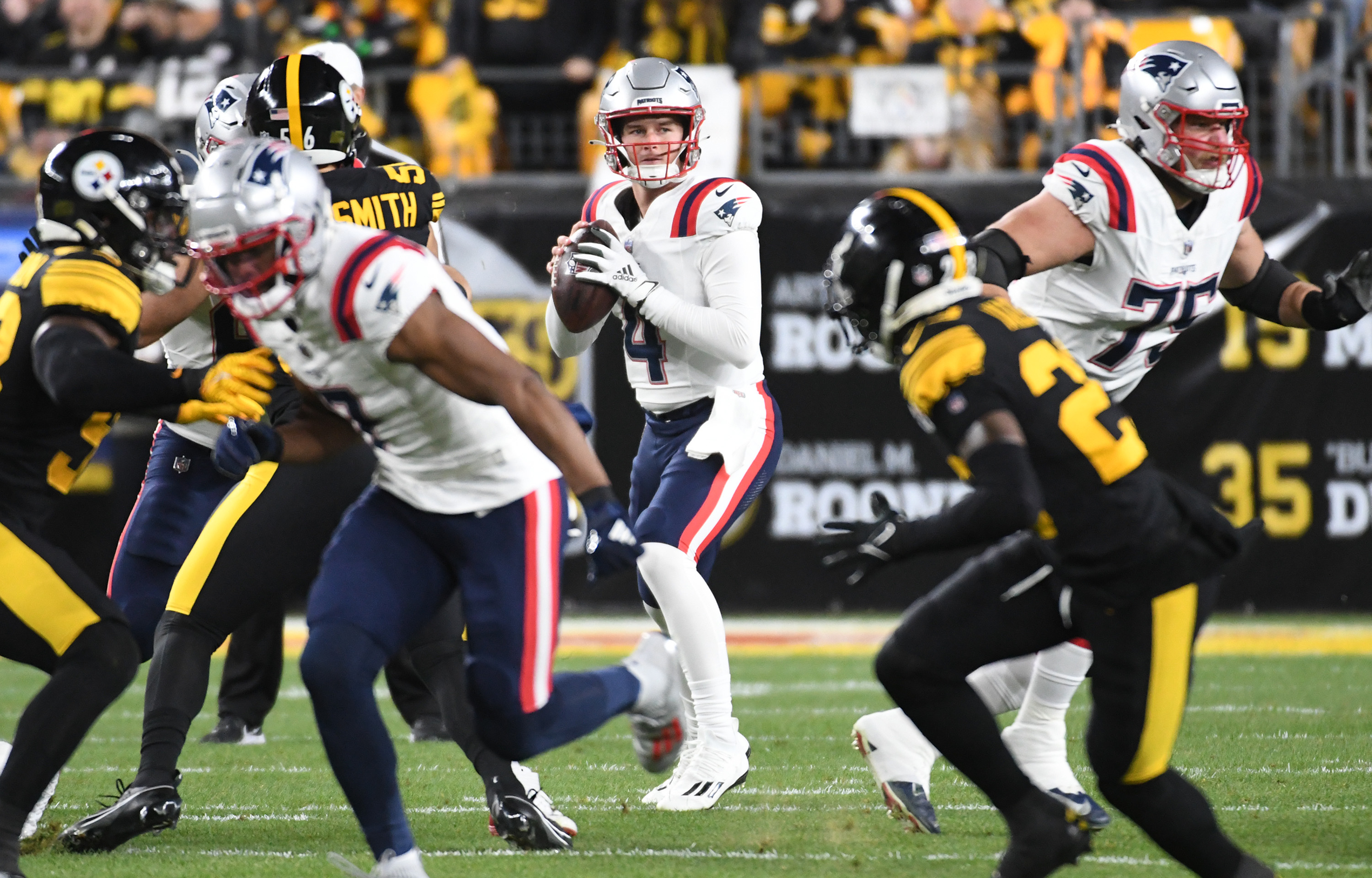 New England Patriots quarterback Bailey Zappe (4) looks for a receiver against the Pittsburgh Steelers during the first quarter at Acrisure Stadium.